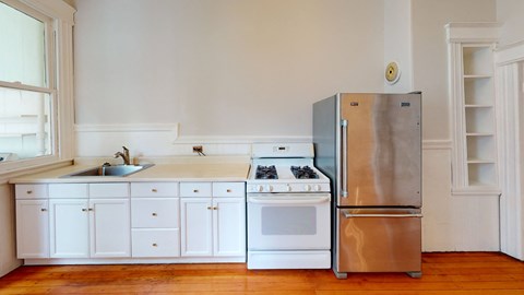 an empty kitchen with white cabinets and a stainless steel refrigerator